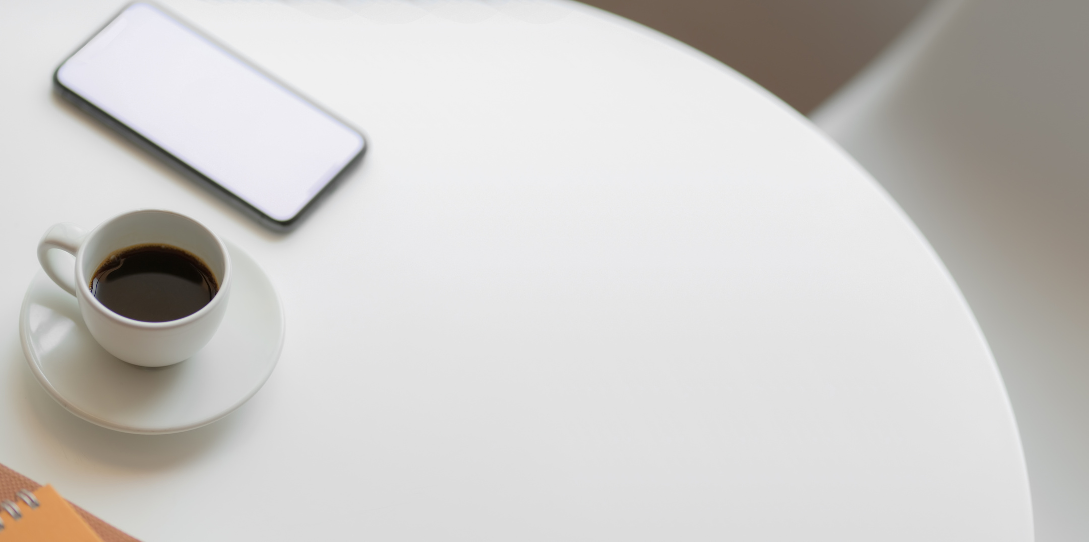 Cup of coffee and smartphone placed on white round table